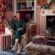 a woman sitting in a chair next to a dog and bookshelf full of books