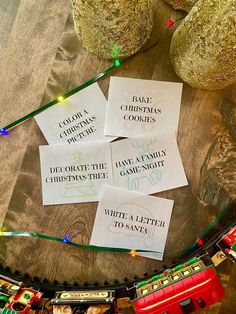 four christmas cookies are sitting on top of a train track next to some ornaments and lights