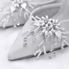 a pair of white wedding shoes with beaded flowers on the side and pearls in the heel