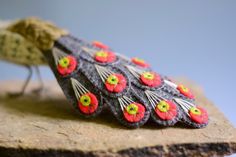 a close up of a small toy bird on a rock with flowers painted on it