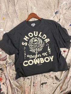 Shoulda Been A Cowboy Cropped T- shirt available in Faded Black and Faded Navy Lava wash Model is 5ft 4 wearing a size Small Size S: Length measures 21” from shoulder to hem with a 20” bust Size M: Length measures 21.5” from shoulder to hem with a 21” bust Size L: Length measures 22” from shoulder to hem with a 22” bust This Crop Jersey Tee slides right into streetwear style for Summer and Winter.. With oversized sleeves and a relaxed body, this on-trend tee drops a little lower in the back for Outfit Ideas Shirt, Shirt Outfit Ideas, Shirt Design Ideas, Panther Shirts, Oversized Sleeves, Carhartt Shirts, Western Graphic Tees, Oversize Sleeves, Streetwear Style