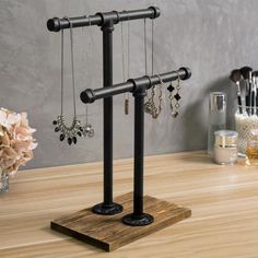 a pair of black metal jewelry stands on top of a wooden table next to flowers