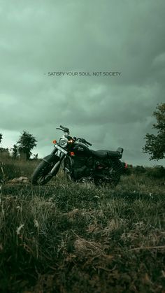 a motorcycle parked in the grass on a cloudy day with an inspirational quote above it