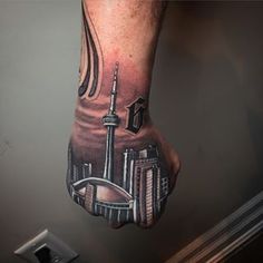 a man's hand with a tattoo on it and a cityscape in the background