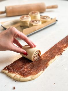 a person rolling out some food on top of a table next to baking utensils