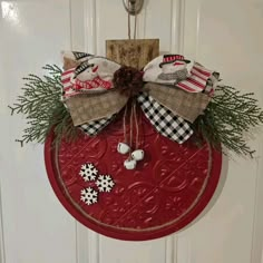 a red door hanger decorated with burlock, snowflakes and pine cones