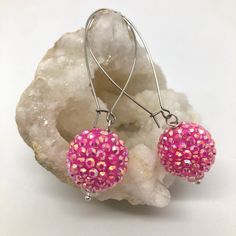 Introducing these pink sparkle ball earrings, the perfect accessory to elevate your everyday fancy style with a touch of modern fun. Crafted with meticulous attention to detail, these earrings are designed to make a statement and accentuate your unique fashion sense. Each earring features a large bead covered in pink rhinestones, angled to catch the light and send it back out into the world. The earrings are suspended from long silver-tone kidney wires, offering a graceful dangle that enhances t Nickel-free Pink Jewelry For Party, Handmade Pink Crystal Drop Earrings, Pink Hypoallergenic Jewelry For Parties, Pink Hypoallergenic Party Jewelry, Hypoallergenic Crystal Earrings For Party, Pink Nickel-free Round Bead Earrings, Pink Nickel-free Round Beaded Earrings, Pink Round Beads Earrings Nickel Free, Nickel Free Pink Round Bead Earrings