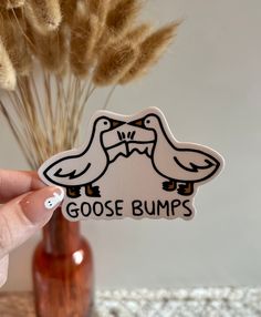 a person holding up a sticker with two birds on it and the words goose bumps