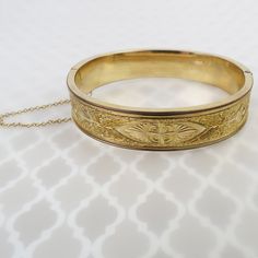 A lovely chased and engraved detailed floral design decorates both sides of this vintage Deco gold filled bangle. Thick linear trim frames the imagery. This piece looks beautiful on its own, but would also be a fun stacking bangle.  The bracelet opens with a working push-button clasp and closes securely. It has a sturdy 1.5mm safety chain for added security. The total inner circumference of the 1/2 inch wide bangle measures approx. 6 3/4 inches. Please see below for more detailed measurements.  The bracelet is in very good condition with expected surface wear. There are a few small dings to the edge of one side of the bracelet. The bracelet tested as gold filled (no hallmarks present). Overall, this piece is in very good working condition with minimal wear for its age. Wt: 18.1 grams Total Vintage 14k Stamped Yellow Gold Bangle, Vintage 14k Stamped Gold Bangle Bracelet, Vintage 14k Stamped Gold Bangle, Vintage Etched Yellow Gold Bangle, Victorian Etched Cuff Bracelet For Wedding, Vintage 14k Gold Bangle, Antique Etched Bangle For Wedding, Victorian Gold Wedding Bracelet Stamped 14k, Victorian Gold Bracelet For Wedding