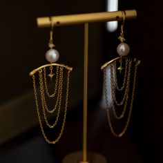 Earrings inspired by the decorative capitals of ancient Greek temple architecture. An item with a series of hanging golden chains that look like tassels. The lustrous pearls give off a lustrous light. A retro item with an exotic scent. 
 
 
 Type 
 
 Earrings 
 
 
 Size 
 
 Height: 8.4cm 
 Width: 2.7cm 
 
 
 Material 
 
 Silver925 
 Alloy 
 Natural pearl 
 
 
 Others 
 
 If you have a metal allergy or the plating does not suit your skin, please refrain from ordering. Elegant Chandelier Earrings With Latkans As Gift, Elegant Gold Chandelier Earrings With Latkans, Gold Pearl Chandelier Earrings For Evenings, Elegant Gold Chandelier Earrings With Dangling Beads, Elegant Pearl Earrings With Latkans, Elegant Brass Chandelier Earrings With Latkans, Elegant Chandelier Earrings With Adjustable Chain, Elegant Gold Chandelier Earrings With Pearl Chain, Elegant Gold Pearl Earrings With Latkans