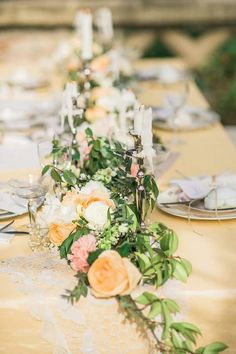 a long table with flowers and candles on it is set for an elegant dinner party