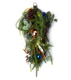 a christmas wreath with pine cones, evergreens and blue baubles hanging from it