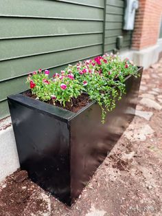 a metal planter filled with flowers on the side of a building