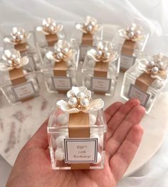 a hand holding a small clear box filled with tiny white flowers and pearls on it