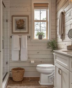 a white toilet sitting next to a window in a bathroom