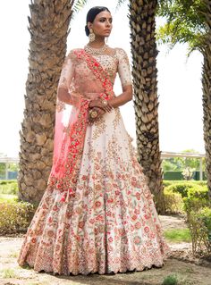 a woman in a white and pink lehenga