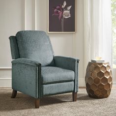 a blue chair sitting next to a vase on top of a carpeted floor in front of a window