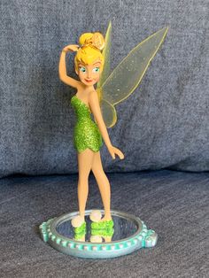 a figurine of a tinkerbell fairy standing on top of a glass plate