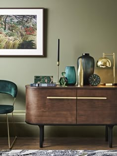 a green chair sits in front of a dresser with various vases and other items on it