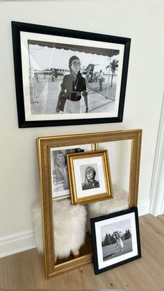 two framed pictures are sitting on the floor next to a shelf with photos and other items