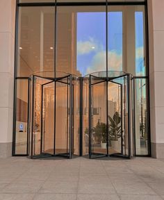 an open glass door on the side of a building with a clock in it's center