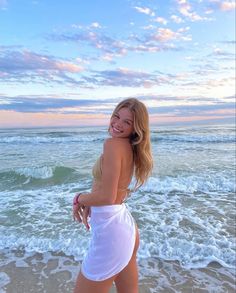 a woman in a white dress standing on the beach