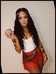 a woman with long hair and tattoos on her body holding a glass in one hand