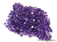 purple glass beads are scattered on a white surface