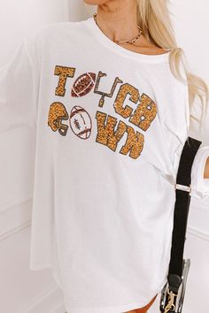 - Football, but make it fabulous with this shimmering tee! Its unique sequined design makes it a perfect addition to any sporty fashionista's game day collection. Stay at the top of the tailgate game with this sporty-chic piece! - Unlined 100% cotton material - A sequined white, black, gold, and brown hued 'TOUCHDOWN' design featuring footballs, a goal post, and a helmet - A crew cut neckline - Short, loose sleeves - A relaxed silhouette that ends in a straight hemline - This piece is perfect fo Touch Down, Crew Cut, Kansas State, Loose Sleeves, Crew Cuts, Final Touch, Sporty Chic, Florida State, Oversized Tee