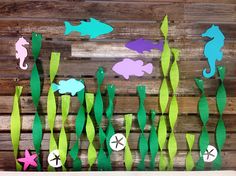 some paper cut out of seaweed and fish on a wooden board with other items