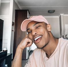 a man with a pink hat is smiling at the camera and has his hand on his chin