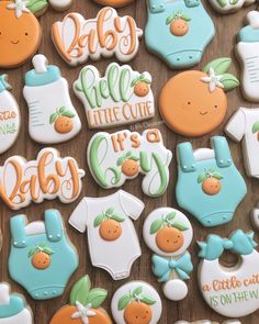 baby shower cookies decorated with blue and orange icing on a wooden table next to other items