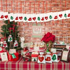 a table topped with lots of presents and christmas decorations next to a red brick wall