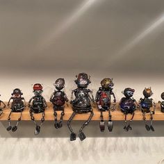 a row of different sized and colored robot figurines sitting on top of a wooden shelf