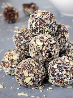 a pile of chocolate covered balls sitting on top of a gray surface next to a bowl