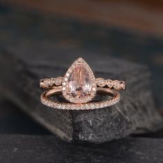 an engagement ring with a pear shaped morganite surrounded by small diamonds on a rock