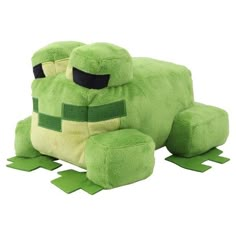 a large green stuffed animal sitting on top of a white floor