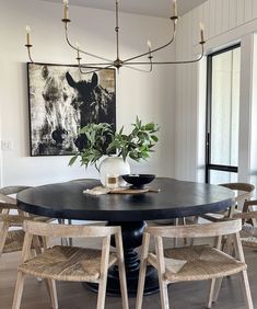 a dining room table with chairs around it and a painting on the wall behind it