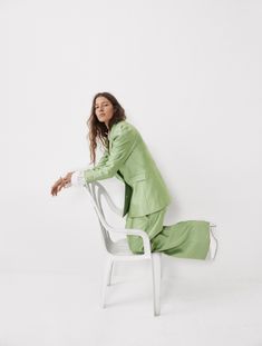 a woman in a green suit sitting on a white chair