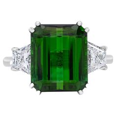 What a rich and classic looking ring! Sure to get compliments every time you wear it. Ring Details: Emerald Cut Chrome Tourmaline (11.7 x 11.3 mm) weighing 6.75 Carats Very Slightly Bluish Green (vslbG) in color with dark tone and moderate saturation (2) Trapezoid-shaped Diamonds weighing 0.95 Carats VS2 Clarity, G Color Total Gem Weight: 7.70 Carats Total Weight of Ring: 4.96 grams Current Ring Size: 5.25 *Resizable Upon Request* Green Platinum Gemstones Fine Jewelry, Fine Green Platinum Gemstones Jewelry, Elegant Green Gemstones For Formal Occasions, Luxury Green Diamond Ring In Platinum, Platinum Green Diamond Ring, Green Diamond Platinum Ring Fine Jewelry, Luxury Trillion Cut Emerald Ring For Formal Occasions, Luxury Tsavorite Gemstones For Anniversary, Fine Jewelry Green Diamond Platinum Ring