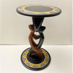 a small black and yellow table with an artistic design on it's base,