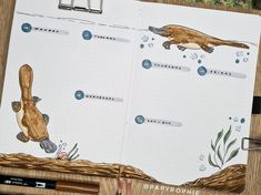 an open notebook with drawings of otters and seaweed on the pages, along with markers