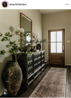 a living room with a rug, vases and mirror on the wall next to it