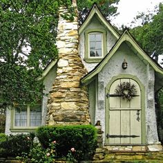 a small house with a stone chimney in the front yard