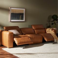 a living room with a brown leather couch and rugs on the floor in front of a window