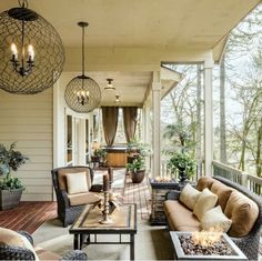 an outdoor living area with couches, tables and lamps hanging from the ceiling above