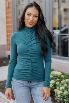 Elevate your style with this Green Cinched Mock Neck Top, which is also available in Red! Designed with long sleeves and a mock neckline, this top offers a sleek and polished look. The cinched front detail creates a flattering, gathered effect that enhances the fitted silhouette. Its versatile design makes it easy to dress up or down, whether paired with high-waisted jeans or a skirt for a night out. Fall Ruched Crew Neck Top, Fall Ruched Tops For Layering, Ruched Tops For Layering In Fall, Ruched Trendy Top For Fall, Ruched Long Sleeve Tops For Winter, Long Sleeve Ruched Winter Tops, Winter Ruched Long Sleeve Tops, Fitted Ruched Tops For Winter, Winter Ruched Fitted Tops