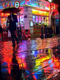 a person with an umbrella is walking down the street in the rain at night time