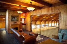 a living room with wood paneling and leather furniture in the center is an open floor plan