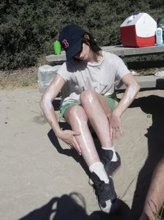 a person sitting on the ground covered in mud with their hands behind their back legs